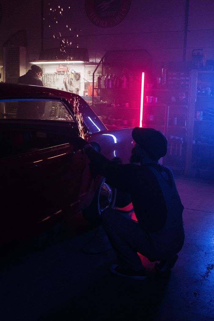 A mechanic repairs a vehicle in a neon-lit garage, enhancing the modern automotive workspace ambiance.